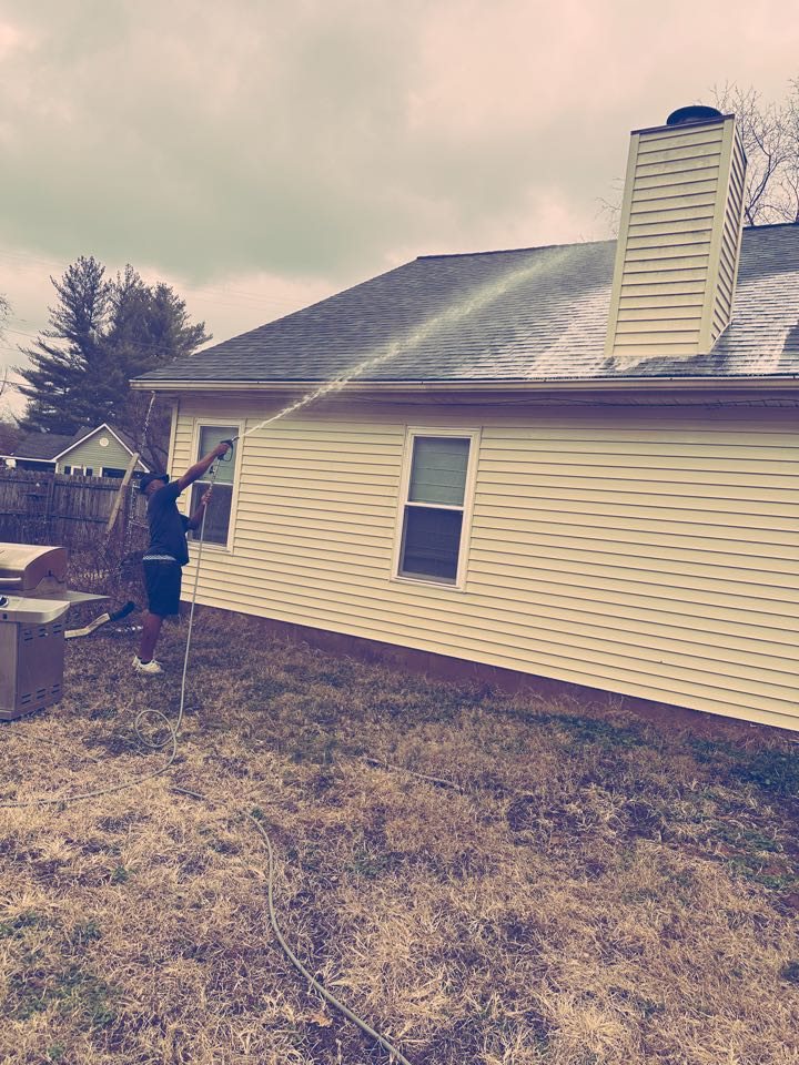 Window Hero Nashville technician washing the yellow siding of a house in Nashville, TN